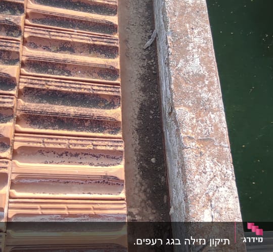 רעפים חומים על גג עם צינור שחור